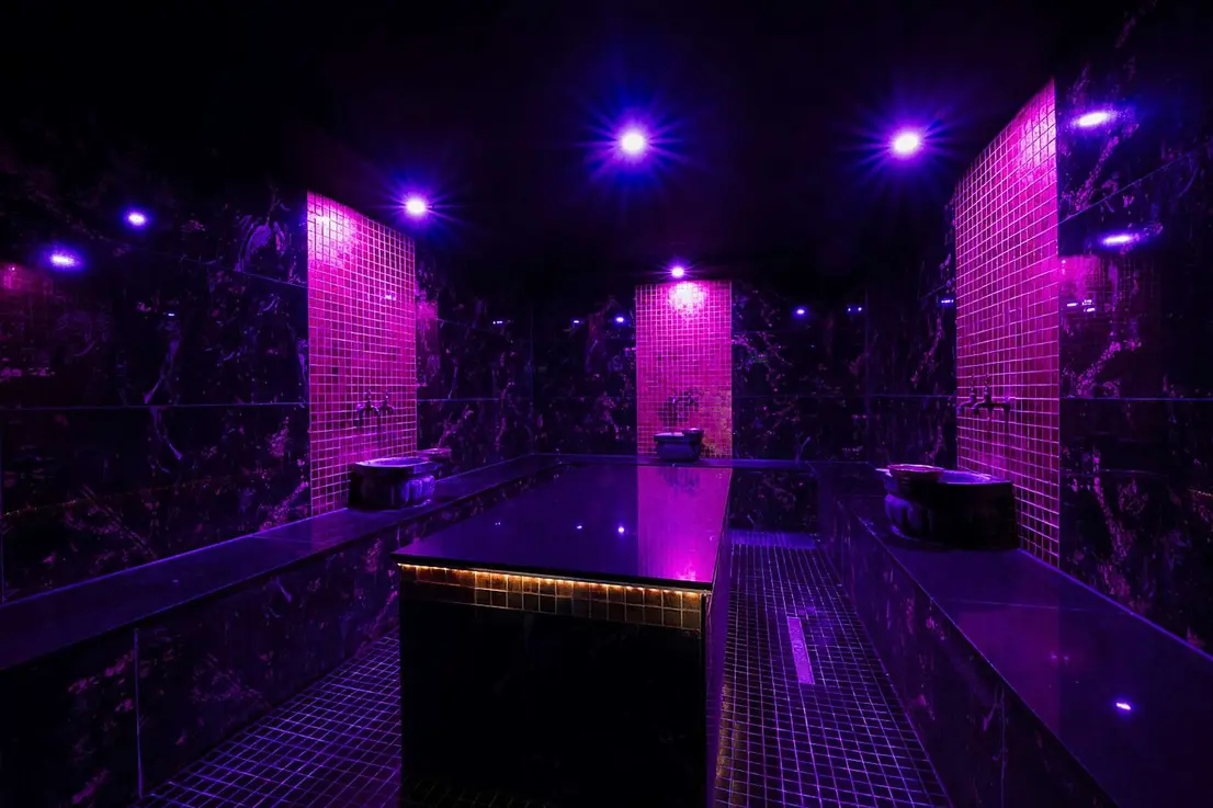 Orientalisches Hamam, gestaltet mit dunklem Naturstein, goldenen Mosaiken und farbigem Licht