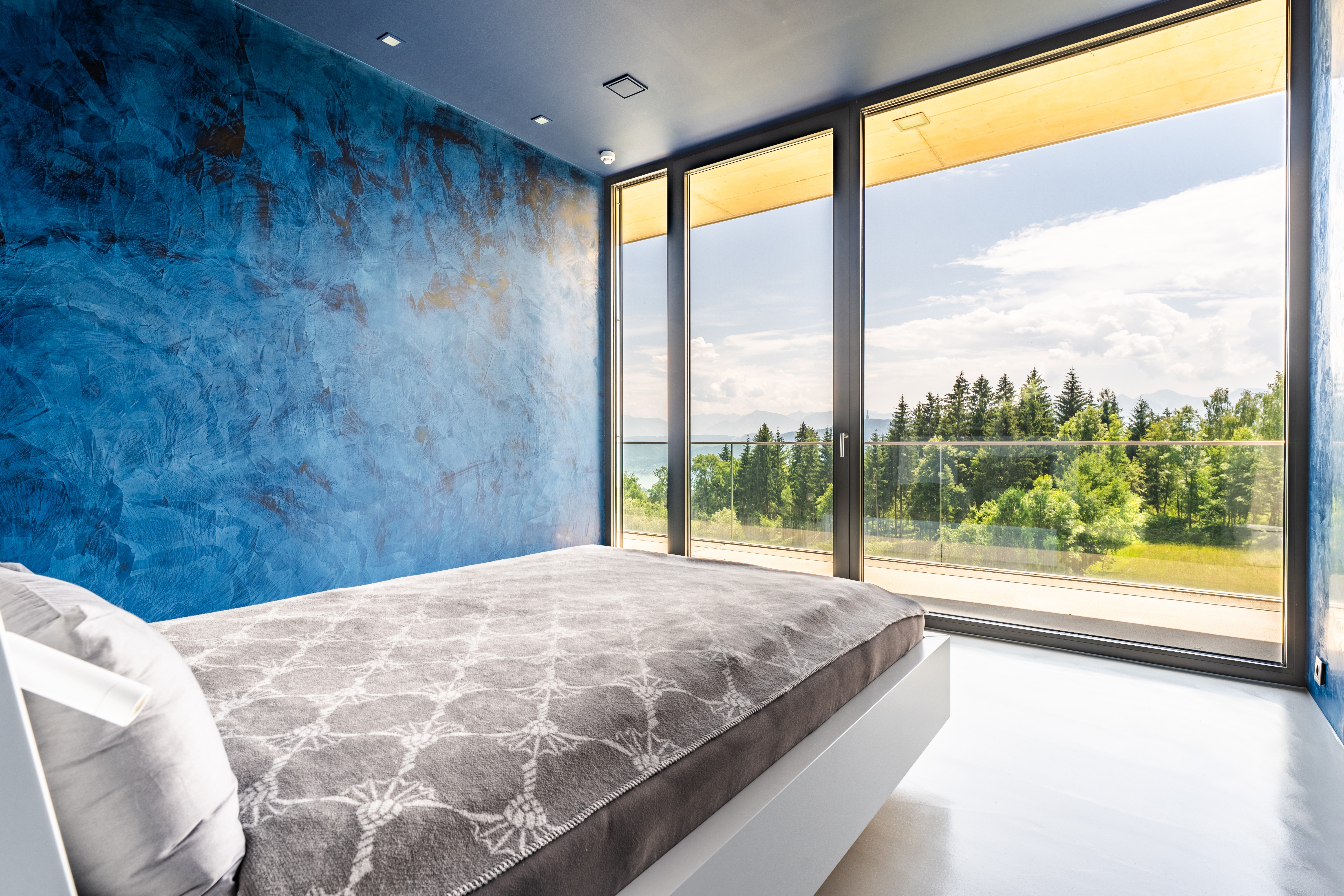 Schlafzimmer mit veredelter blauer Strukturwand und Waldblick
